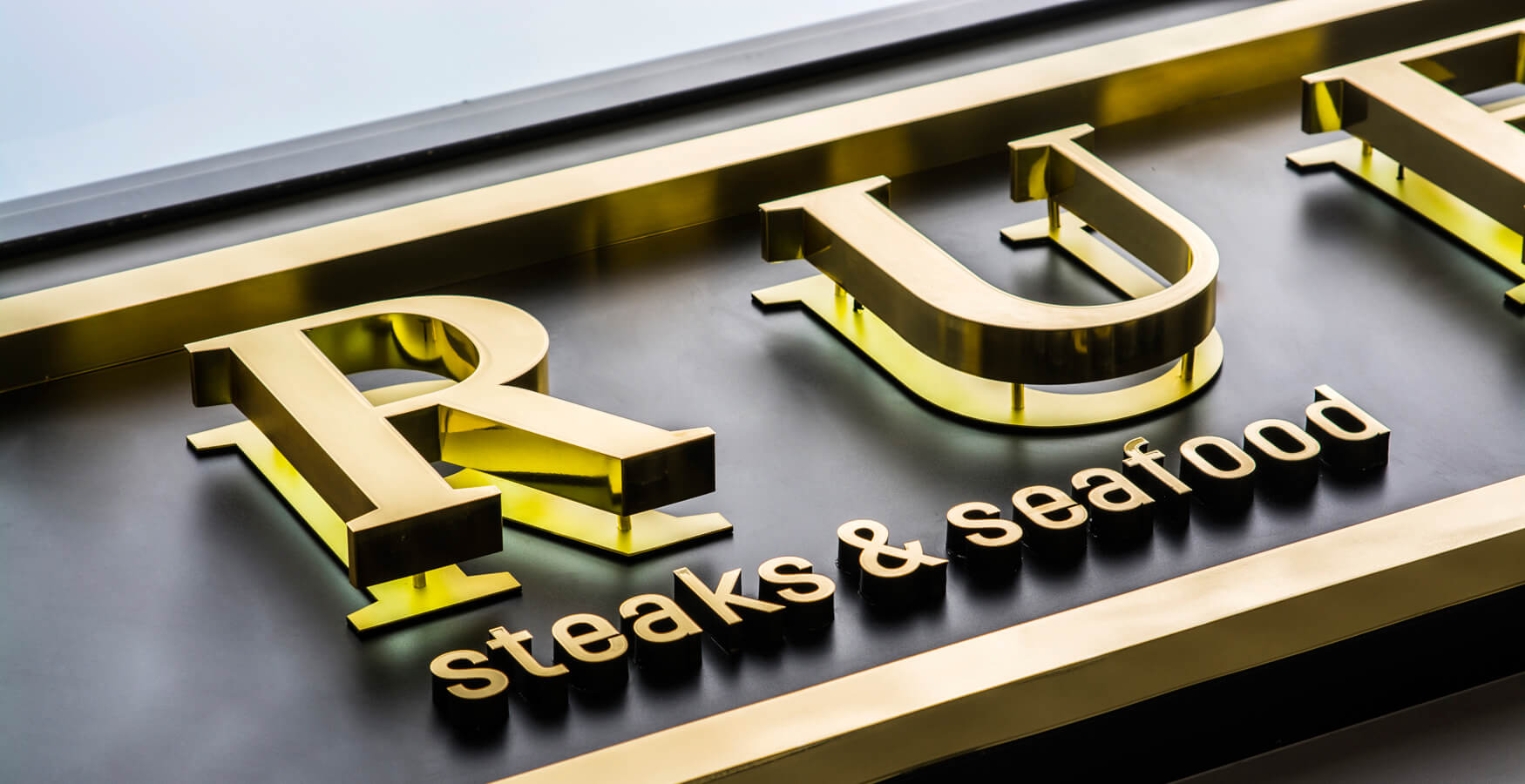 True - outdoor signboard with golden spatial letters made of stainless steel sheet